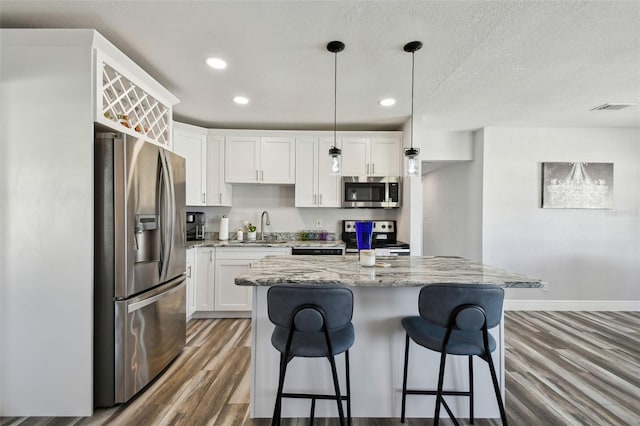 kitchen with hanging light fixtures, white cabinets, appliances with stainless steel finishes, and sink