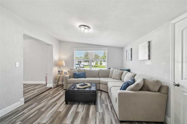 living room featuring vaulted ceiling, a textured ceiling, and hardwood / wood-style flooring