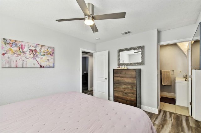 bedroom with ceiling fan, ensuite bath, and dark hardwood / wood-style flooring