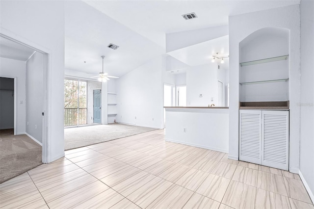 unfurnished living room featuring ceiling fan, light carpet, built in features, and lofted ceiling