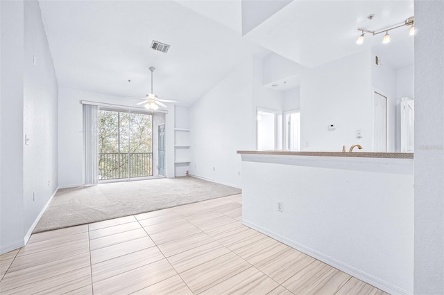 unfurnished living room featuring ceiling fan, built in shelves, vaulted ceiling, and light tile patterned floors