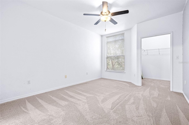 unfurnished bedroom featuring ceiling fan, light colored carpet, a spacious closet, and a closet