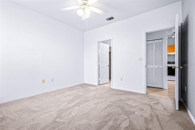 unfurnished bedroom featuring ceiling fan, light colored carpet, and a closet