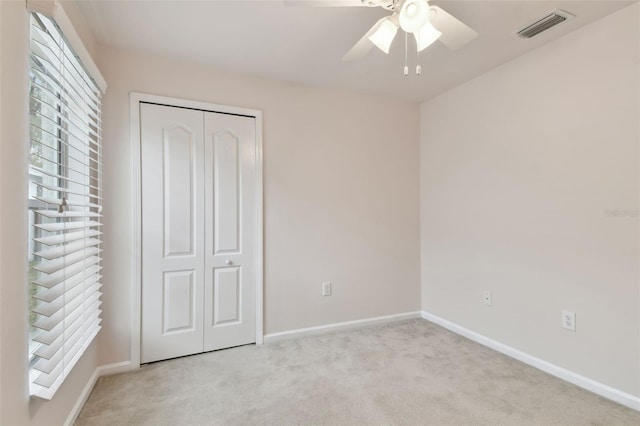 unfurnished bedroom featuring light colored carpet, a closet, and ceiling fan