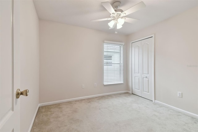 unfurnished bedroom with light colored carpet, a closet, and ceiling fan