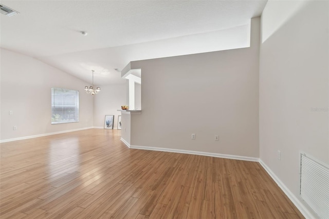 unfurnished living room with light hardwood / wood-style floors, vaulted ceiling, and a notable chandelier