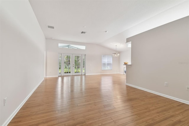 unfurnished living room with vaulted ceiling, a chandelier, light wood-type flooring, and french doors