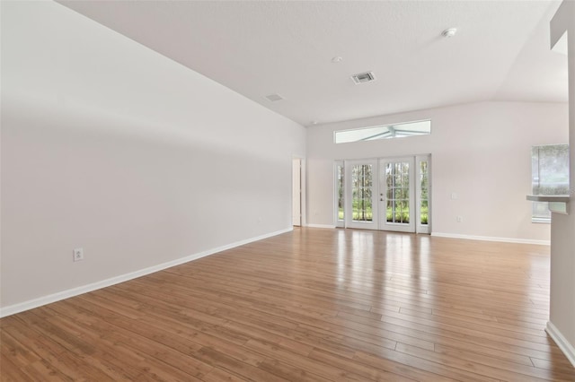 spare room with lofted ceiling, light hardwood / wood-style floors, and french doors