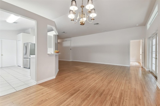 interior space featuring a notable chandelier, vaulted ceiling, and light hardwood / wood-style floors