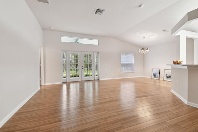 unfurnished living room featuring an inviting chandelier, light hardwood / wood-style floors, french doors, and lofted ceiling