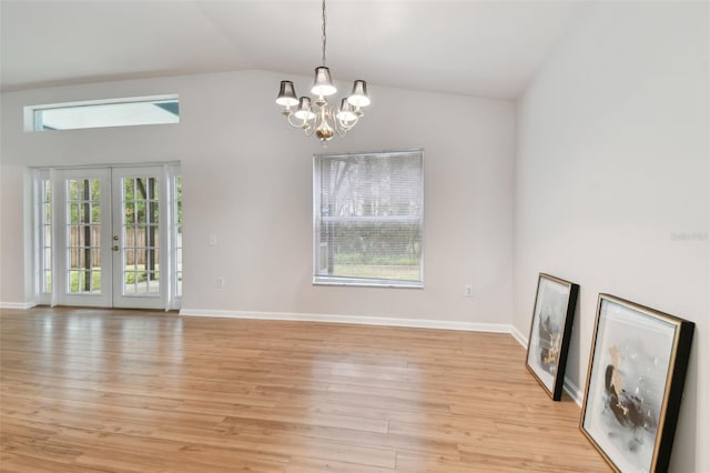 unfurnished living room featuring french doors, lofted ceiling, light hardwood / wood-style floors, and a notable chandelier