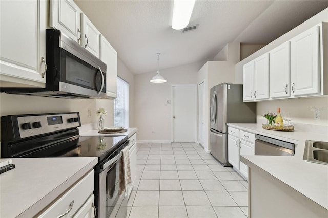 kitchen with vaulted ceiling, appliances with stainless steel finishes, light tile patterned flooring, decorative light fixtures, and white cabinets