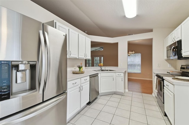 kitchen featuring lofted ceiling, sink, white cabinetry, light tile patterned floors, and appliances with stainless steel finishes