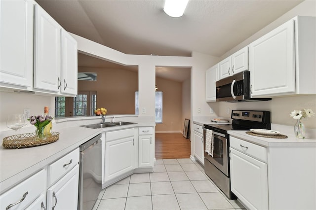 kitchen featuring light tile patterned flooring, white cabinetry, sink, stainless steel appliances, and a healthy amount of sunlight