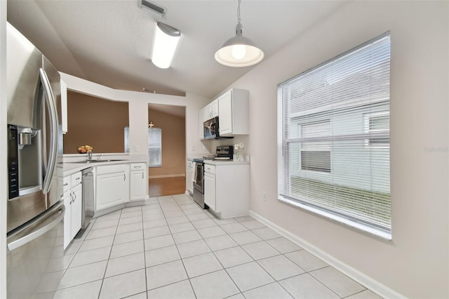 kitchen featuring vaulted ceiling, appliances with stainless steel finishes, light tile patterned floors, and white cabinets