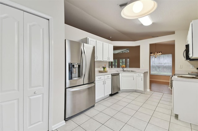 kitchen with lofted ceiling, white cabinets, hanging light fixtures, light tile patterned floors, and stainless steel appliances