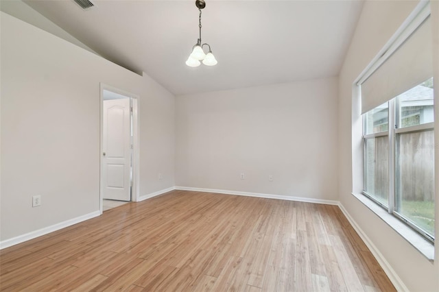 unfurnished room with vaulted ceiling, an inviting chandelier, and light hardwood / wood-style floors