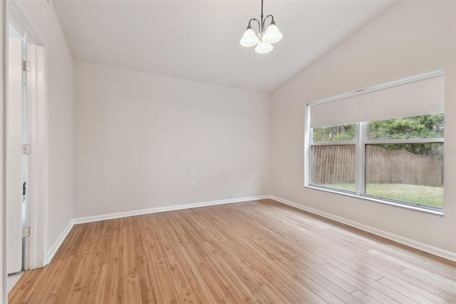 empty room with lofted ceiling, light hardwood / wood-style floors, and a chandelier