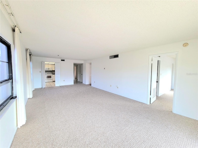 unfurnished living room featuring light colored carpet and a textured ceiling