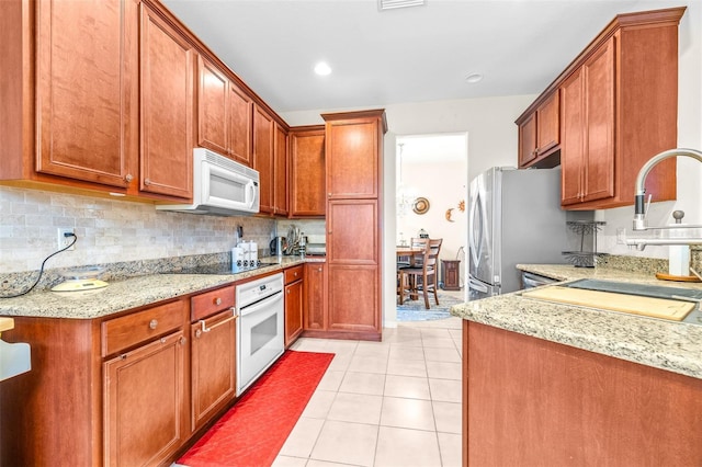 kitchen featuring light stone countertops, white appliances, decorative backsplash, sink, and light tile patterned floors