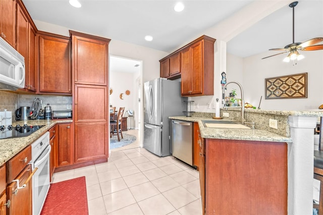 kitchen with light tile patterned floors, light stone countertops, sink, and stainless steel appliances