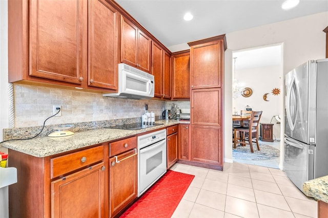 kitchen featuring light tile patterned floors, backsplash, light stone countertops, and white appliances