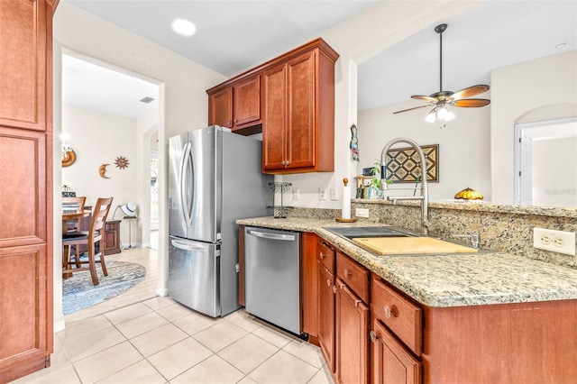 kitchen featuring ceiling fan, sink, stainless steel appliances, light tile patterned floors, and light stone counters