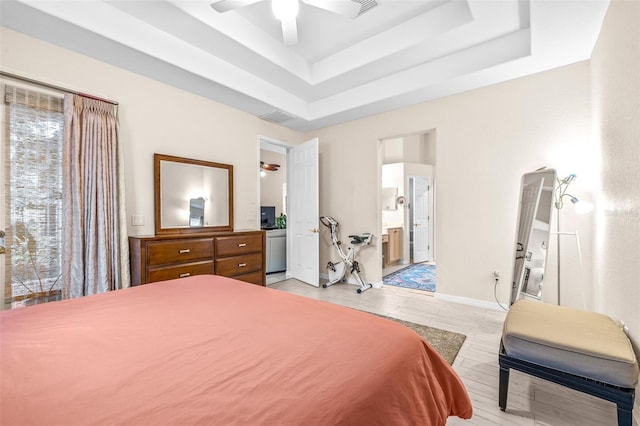 bedroom with ceiling fan, a tray ceiling, connected bathroom, and multiple windows