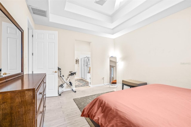 bedroom featuring light wood-type flooring and a tray ceiling