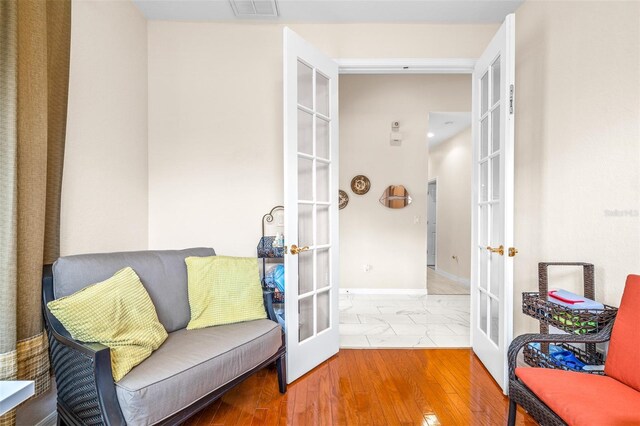 living area with hardwood / wood-style floors and french doors