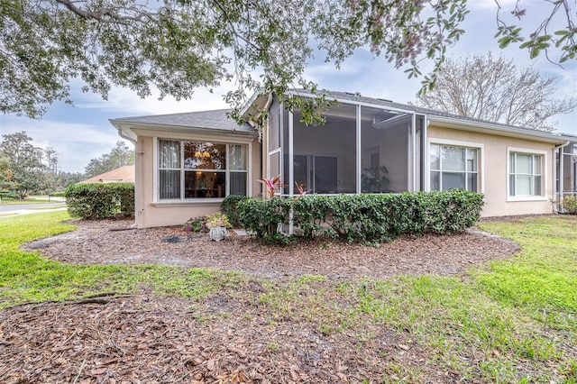 view of property exterior featuring a sunroom and a lawn