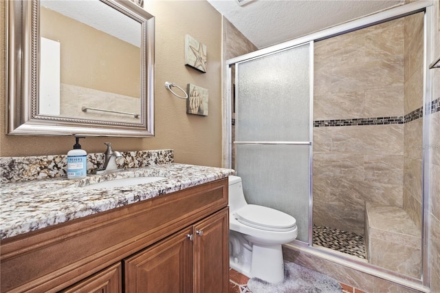 bathroom featuring a textured ceiling, an enclosed shower, vanity, and toilet