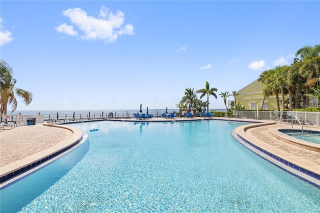 view of swimming pool featuring a hot tub and a water view