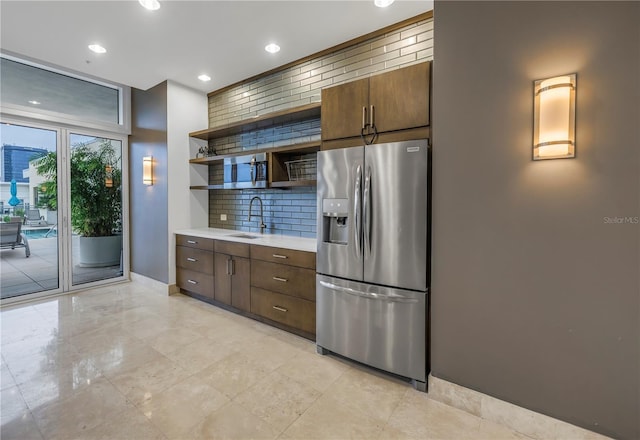 kitchen featuring sink, stainless steel fridge, dark brown cabinets, and tasteful backsplash