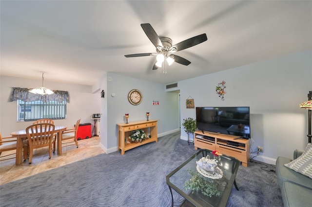 carpeted living room with ceiling fan with notable chandelier