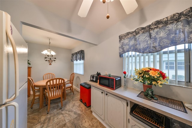 kitchen with white refrigerator, ceiling fan with notable chandelier, and hanging light fixtures