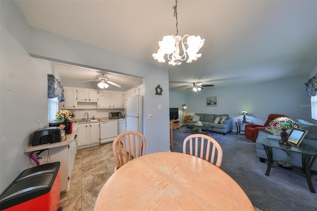 dining space with ceiling fan with notable chandelier and sink