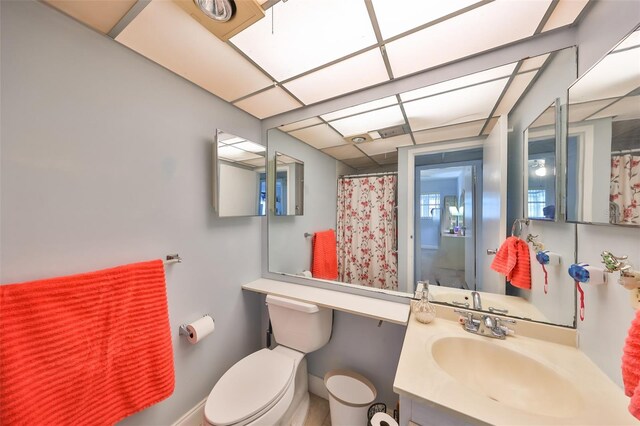 bathroom featuring a drop ceiling, vanity, and toilet