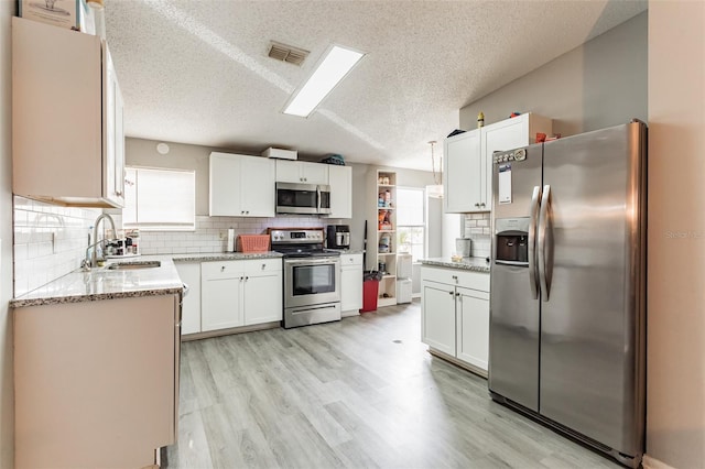 kitchen featuring a textured ceiling, stainless steel appliances, white cabinets, and sink