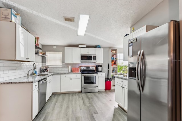 kitchen featuring white cabinets, backsplash, stainless steel appliances, and a textured ceiling