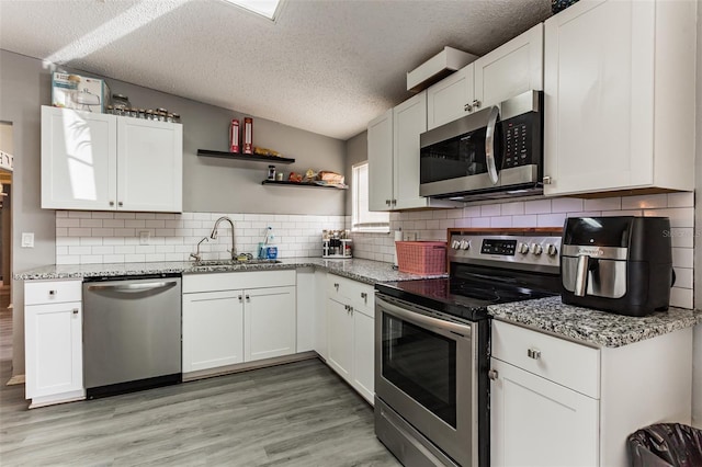 kitchen with white cabinets, stainless steel appliances, and a textured ceiling