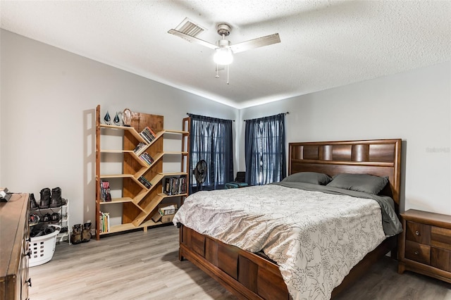 bedroom featuring light wood-type flooring, ceiling fan, and a textured ceiling