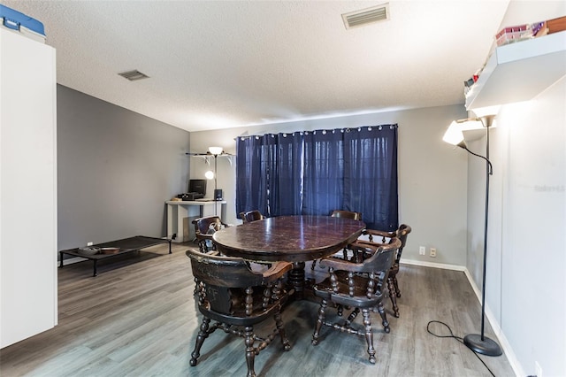 dining space with a textured ceiling and hardwood / wood-style flooring