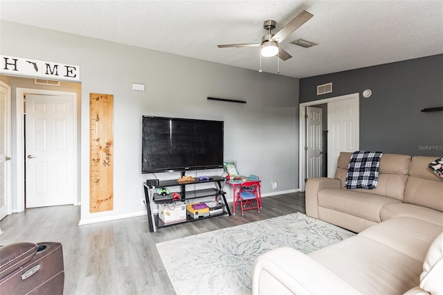 living room with ceiling fan, a textured ceiling, and hardwood / wood-style flooring