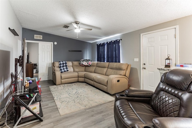 living room featuring a textured ceiling, ceiling fan, and light hardwood / wood-style floors