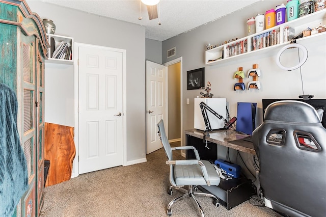 carpeted office space featuring ceiling fan and a textured ceiling