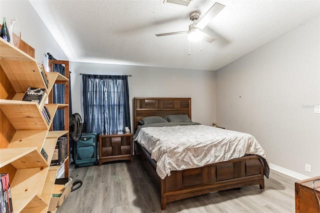 bedroom with ceiling fan, hardwood / wood-style floors, and a textured ceiling