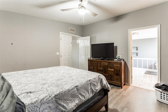 bedroom featuring a textured ceiling, ceiling fan, ensuite bathroom, and light wood-type flooring