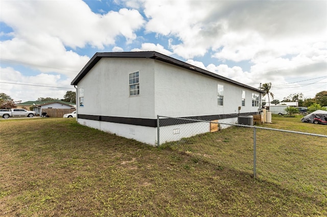 view of side of property featuring central air condition unit and a yard