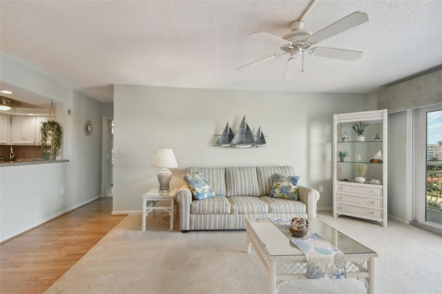 living room featuring ceiling fan, light colored carpet, and a textured ceiling